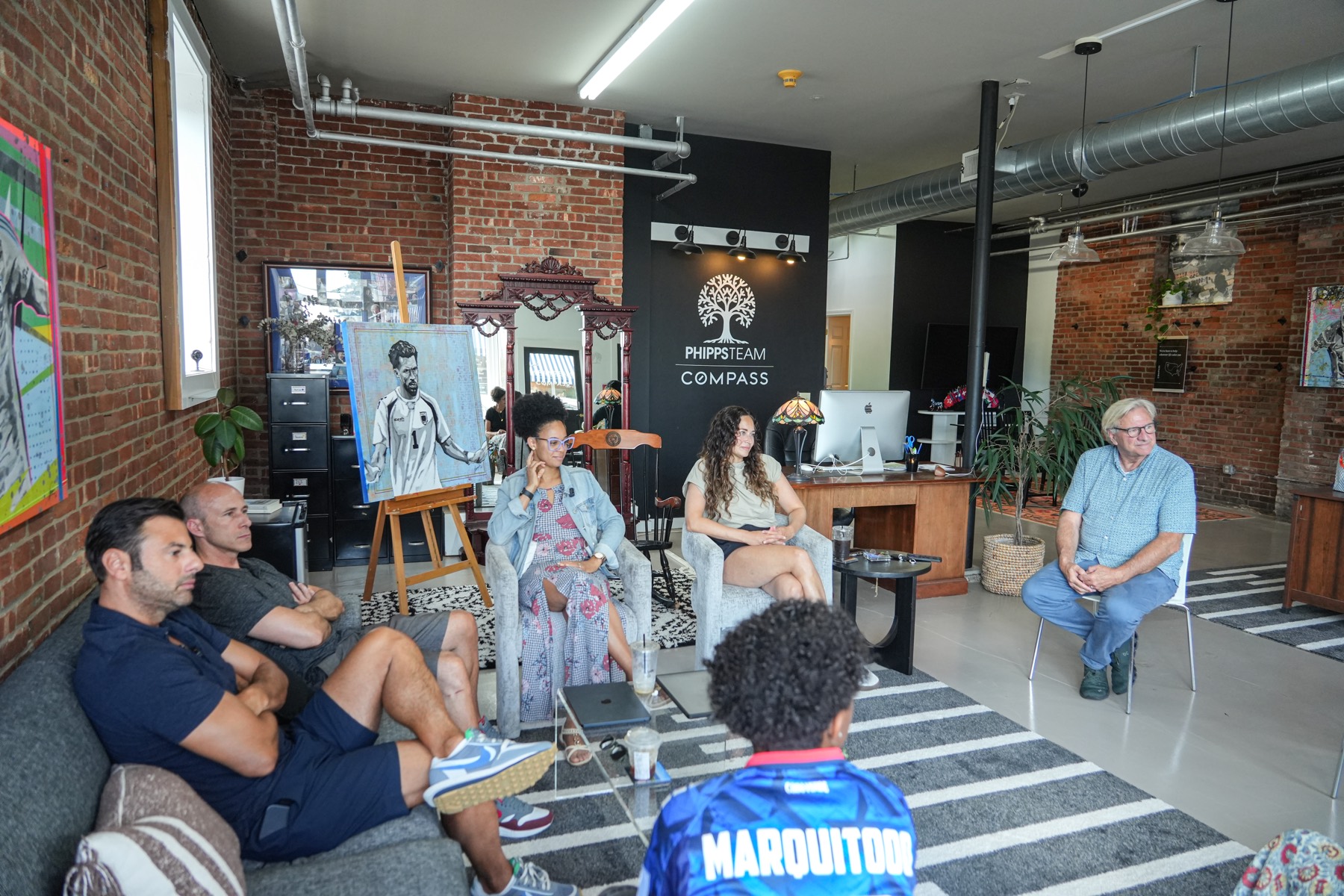 A group in conversation in a brick-walled loft