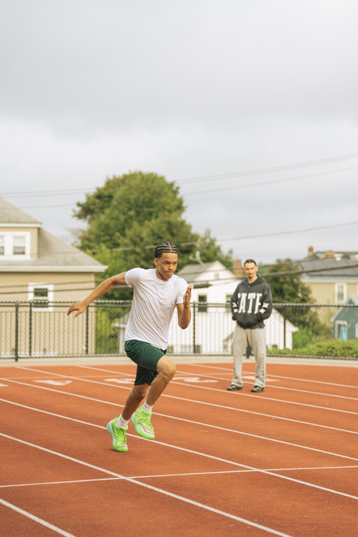A sprinter coming out of the blocks while a coach watches