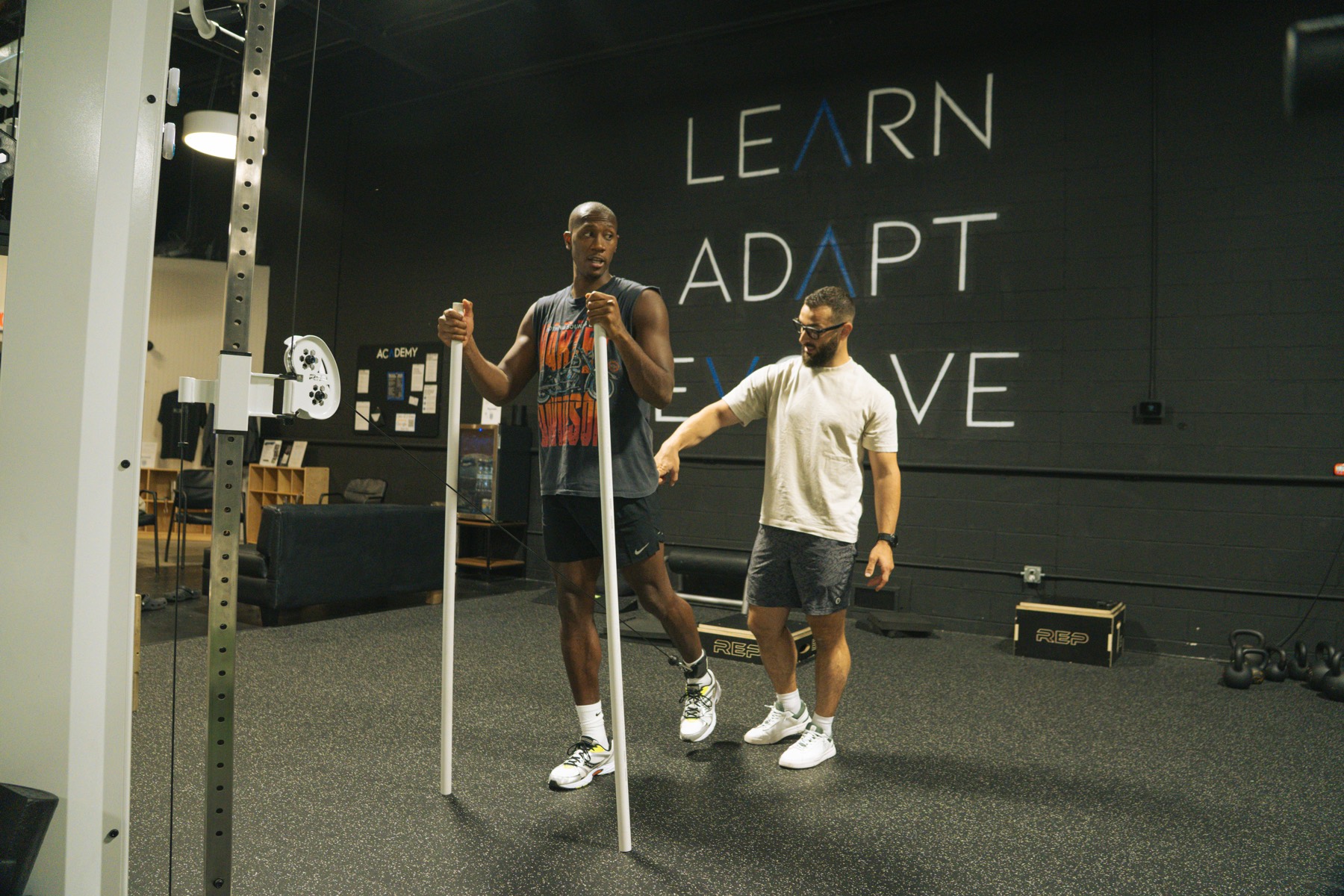 A coach guiding an athlete through a movement in the weight room